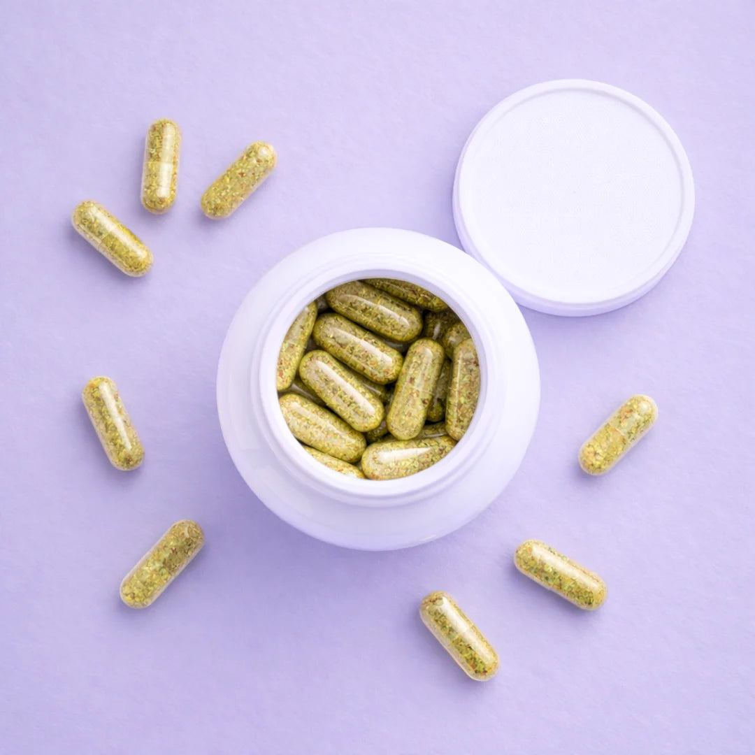 Gold capsules of Balance around a white container on a purple background